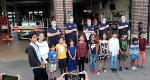 Children from Reading Balagokulam tying rakhi to firefighters at Reading Town Fire Station during Raksha Bandhan celebration